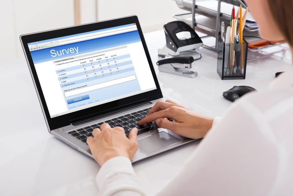 Image shows the a person completing the Voice of Customer Form on a laptop at a desk.