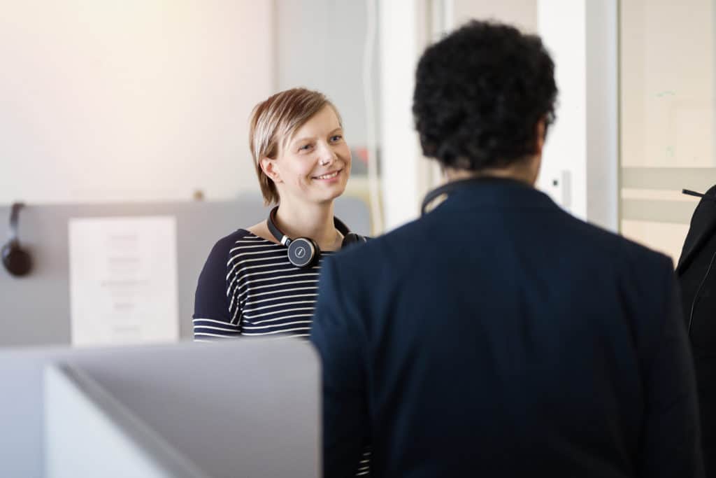 Image shows employees engaging with one another in an office environment. 