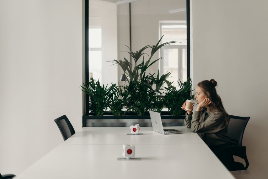 Image shows a woman sat alone working at a large table representing the introverted employees experience.