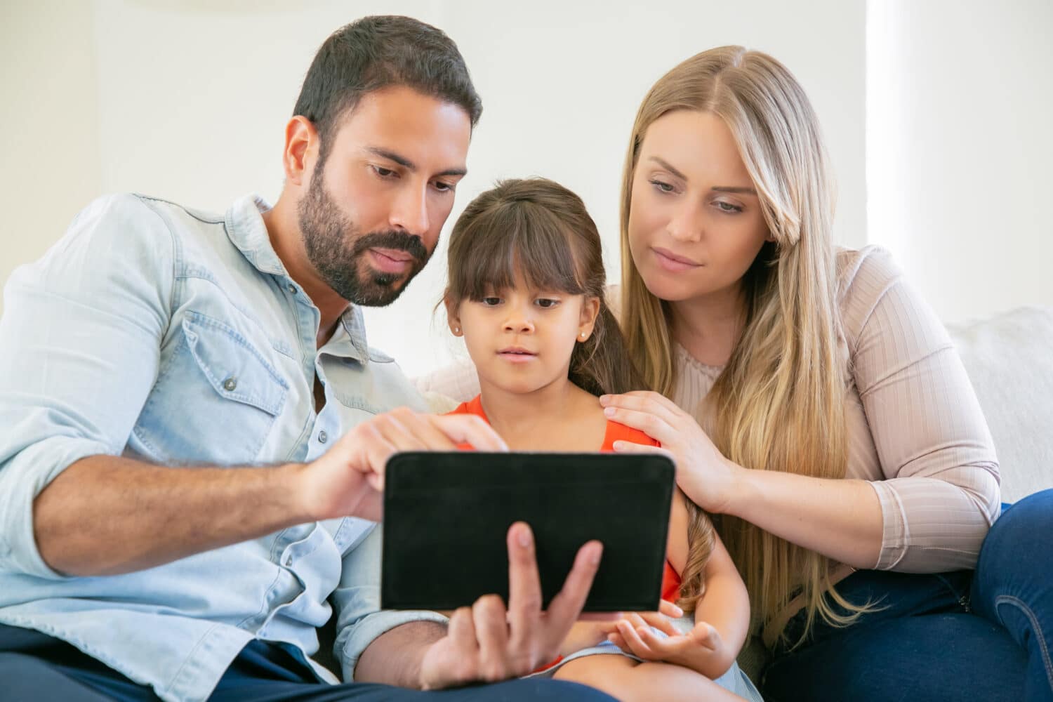 Young family sitting on the couch checking for insurance plans digitally.
