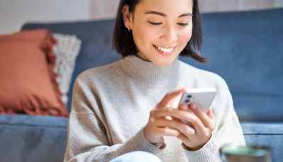 Smiling woman using her mobile phone at home, illustrating a seamless omnichannel insurance customer experience